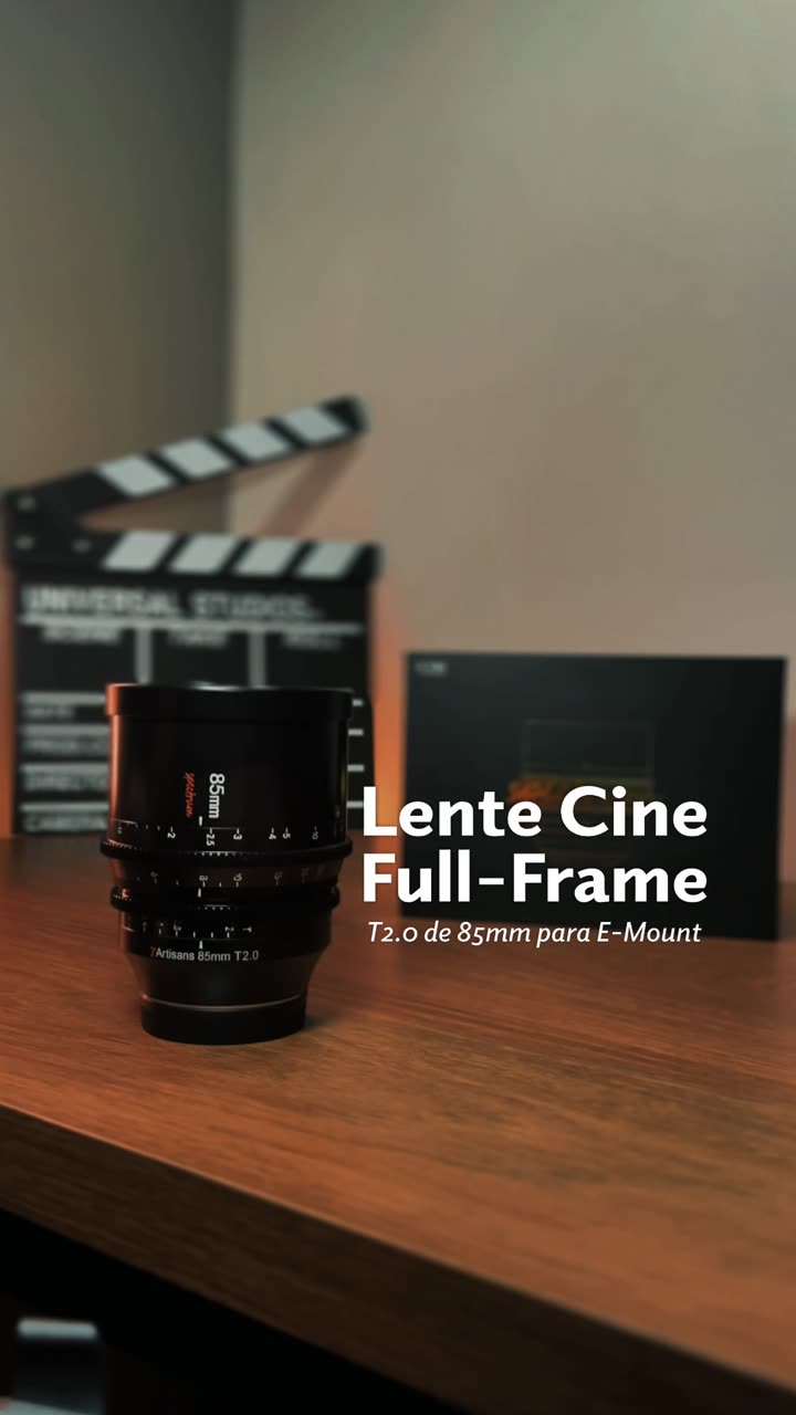 Mãos apoiando uma lente cinema sobre mesa de madeira, com claquete ao fundo.