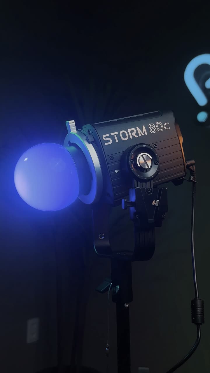 Luz de LED Storm 80c montada em tripé com difusor esférico, em sala escura.